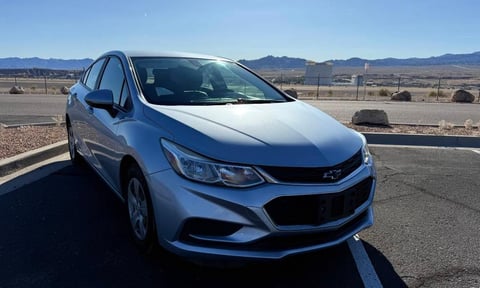 Blue Chevrolet Cruze sedan parked in a desert lot with mountains in the background under clear sky