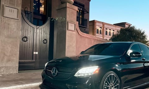 Black Mercedes-Benz sedan parked in front of an ornate building with terracotta architecture and gated entrance