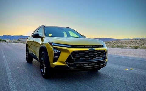 Bright yellow and black Chevrolet Trailblazer SUV parked on desert road with mountains in background