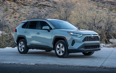 Light blue Toyota RAV4 SUV parked on asphalt with desert brush in the background